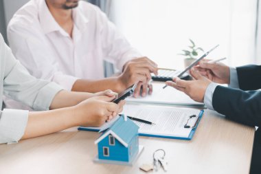 Ev modeli, arka planda sözleşme, emlak yatırımı konsepti, ipotek kredisi, ev sahipliği, gayrimenkul ticareti ve mali anlaşma konularını tartışan bulanık insanlarla birlikte masada..