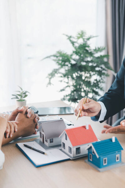 Крупный план агента по недвижимости, показывающего клиенту модель маленького дома с калькулятором, контрактные документы на столе, концепция ипотечного кредита, владение домом, инвестиционный договор с недвижимостью. ипотечный кредит