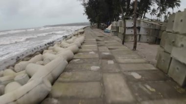 Beton bloklar ve ağaçlarla sahil şeridinde taş yol.