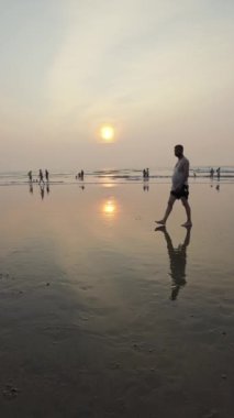 Kumsalda gün batımı Rolling Waves ve akşamları eğlenen insanlar