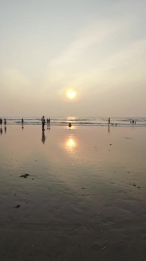 Kumsalda gün batımı Rolling Waves ve akşamları eğlenen insanlar