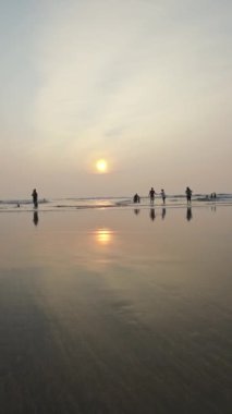 Kumsalda gün batımı Rolling Waves ve akşamları eğlenen insanlar