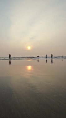 Kumsalda gün batımı Rolling Waves ve akşamları eğlenen insanlar