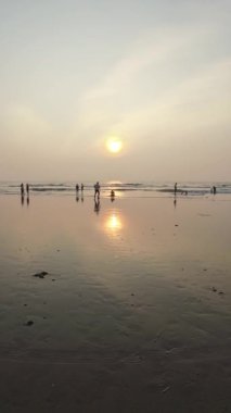 Kumsalda gün batımı Rolling Waves ve akşamları eğlenen insanlar