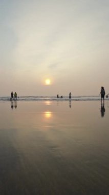 Kumsalda gün batımı Rolling Waves ve akşamları eğlenen insanlar