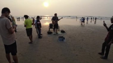 Gün batımında Gitarla Sahilde Şarkı Söyleyen Adam