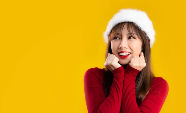 Asian woman long hairstyle in red long sleeve t-shirt wear santa hat posing yellow background.