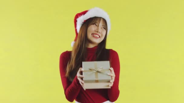 亚洲女人笑着与黄色背景的圣诞礼品盒共舞 带着礼物的快乐女孩寒假快乐新年快乐的概念 — 图库视频影像