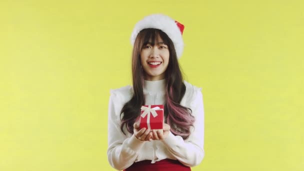 亚洲女人笑着把圣诞礼物盒放在黄色的背景上 带着礼物的快乐女孩寒假快乐新年快乐的概念 — 图库视频影像