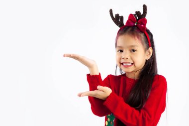 Kırmızı kazaklı küçük Asyalı çocuk Noel temalı kostümlü beyaz arka planda poz veriyor..