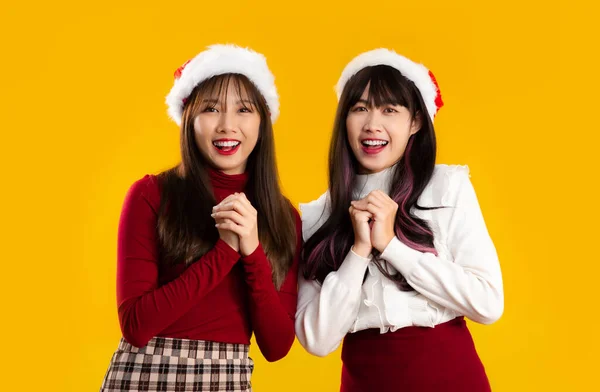 若いですアジアの女性で赤と白のクリスマスの衣装を身に着けているサンタ帽子笑顔とポーズ黄色の背景 — ストック写真