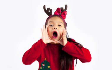 Kırmızı kazaklı küçük Asyalı çocuk Noel temalı kostüm beyaz arka planda bağırıyor.
