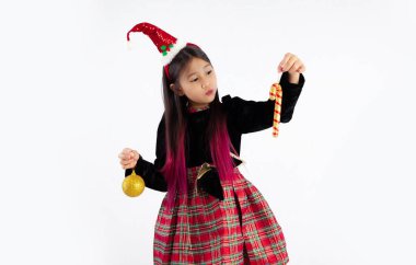 Hoş Asyalı kız uzun saç stili, Noel temalı kostüm, elinde altın top ve şeker kamışlarıyla beyaz arka plandaki Noel ağacını süslemek için..