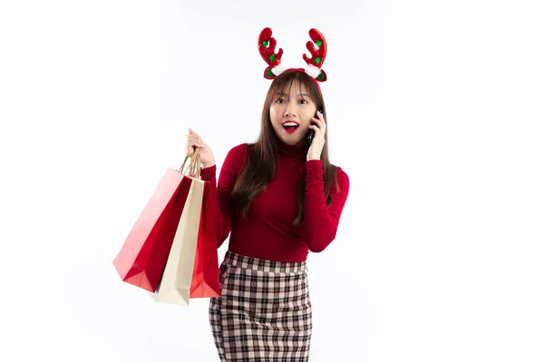 若いですアジアの女性で赤いクリスマスの衣装を呼び出し 白い背景にショッピングバッグを運ぶ — ストック写真