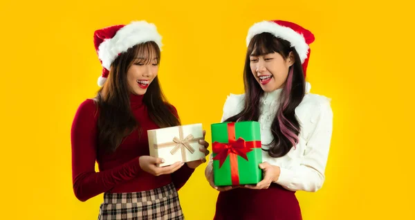 黄色の画面の背景にプレゼントボックスを保持サンタの帽子を身に着けている赤と白の色の服を着た若いアジアの美しい女性 メリークリスマスとハッピーニューイヤー — ストック写真