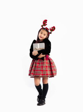 Siyah kazaklı küçük Asyalı kız Noel ve yeni yıl partisini kutlamak için hediye kutusunu beyaz arka planda tutuyor..