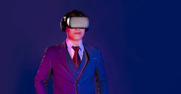 濃い青の背景を見ているVrガラスのヘッドセットを身に着けている若いスマートアジアのビジネスマン メタバースの概念 — ストック写真