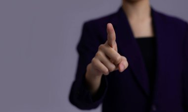 Siyah ceketli kadın, gri arka planda bulanık parmak..