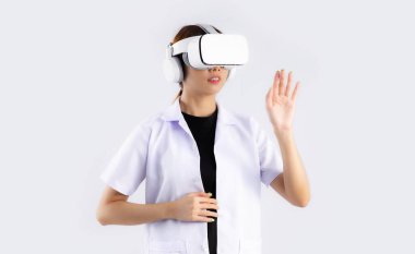 Asian woman doctor wearing vr goggles headset watching and hand touching on white background. Metaverse and medical technology concept.	