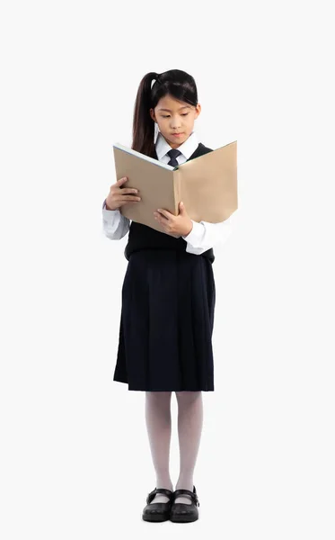 アジアの学生で学校制服立ってフル長さと白の背景に本を読む — ストック写真