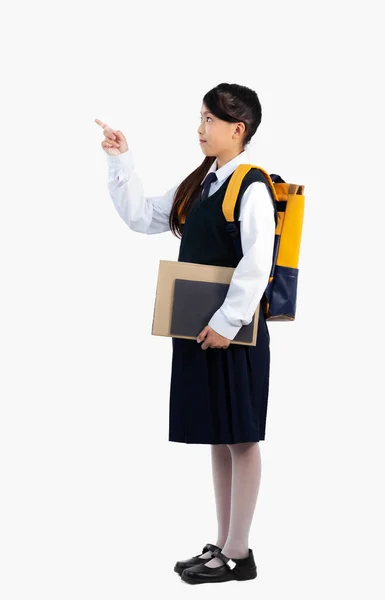学校に戻る アジアの子供中学校女の子で制服を着てバックパックと本指指すフル長さホワイトバックパック — ストック写真