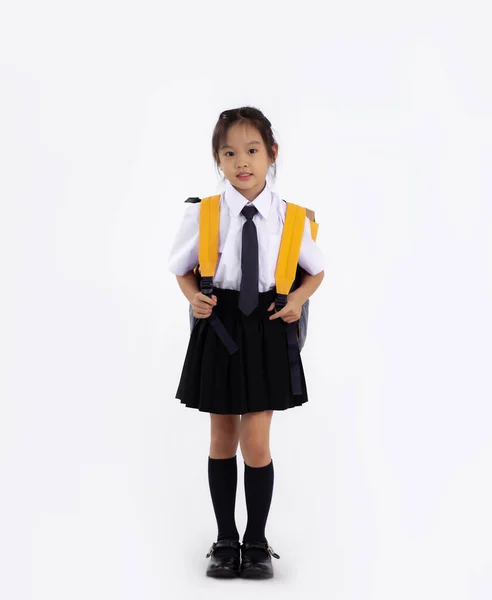Junior school student in uniform with yellow backpack standing full length white background. Back to school