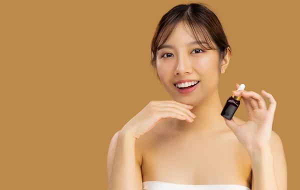 Beauty asian woman portrait face with skin care healthy and skin holding bottle of serum on beige color background.