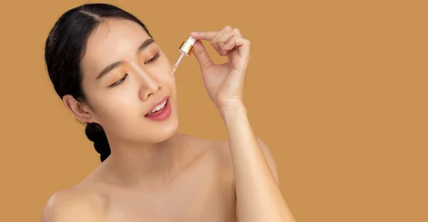 Beauty asian woman portrait dropping essential oil on clean face.