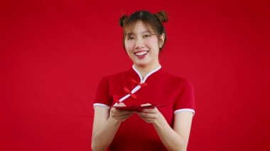 pretty asian woman holding red envelopes red background to celebrate Chinese New Year. 4K video footage