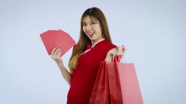 Young asian woman holding red envelopes and shopping bag isolated on white background to celebrate Chinese New Year. 4K video footage