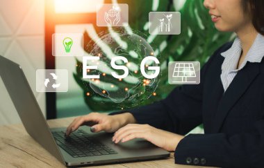 ESG, Çevre Sosyal Yönetimi. Dizüstü bilgisayarla çalışan bir iş kadını. Sürdürülebilir. İş organizasyonunun gelişimi. Kirliliği azaltmak için yenilenebilir kaynak teknolojisi.