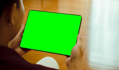 Asyalı adamın elinde siyah dijital tablet tutarken ki görüntüsü evde veya ofiste boş yeşil ekranlı.