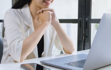 Asian woman using laptop computer working from home office.	