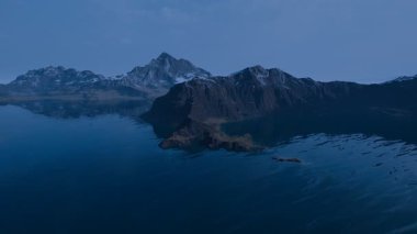 Engebeli karları yansıtan bir dağ gölü manzarası. Suda hafif dalgalanmalar, barışçıl ve sinematik atmosfer. Doğa belgeselleri, seyahat ve meditasyon için mükemmel. 3d oluşturma.