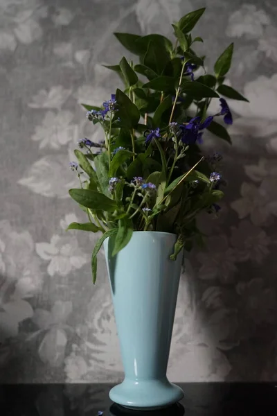 A bouquet of forest light blue flowers Myosotis sylvatica and blue flowers Vinca minor in a vase in April. Berlin, Germany