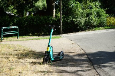 Elektrikli scooter yolun kenarında duruyor. Motorlu scooter, ya küçük bir içten yanmalı motor ya da ön ve arka tekerleğindeki elektrik merkezi motoru tarafından desteklenen bir stand-up mobiletidir. Berlin, Almanya