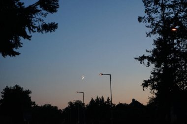 Eylül 'de akşam vakti ay bir yolun üzerinde parlar. Kaulsdorf, Berlin, Almanya