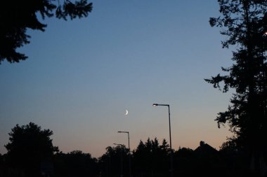 Eylül 'de akşam vakti ay bir yolun üzerinde parlar. Kaulsdorf, Berlin, Almanya