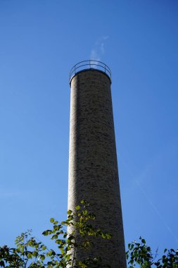 Ekim ayında mavi gökyüzüne karşı kazan dairesinden duman çıkan baca. Berlin, Almanya