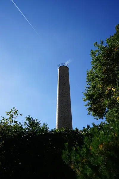 Chimney with smoke from the boiler room against the blue sky in October. Berlin, Germany