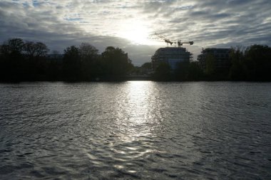 Berlin, Koepenick, Almanya - 3 Ekim 2022: Gün batımında Spree nehrinin kıyısında bir inşaat alanında çalışan bir kule vinci.