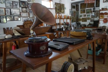 Lardos, Güney Ege bölgesi, Yunanistan - 29 Ağustos 2022: Antik müzik aletleri, fonograflar ve diğer müzik aletleri, radyo cihazları Rodos adasındaki Folklor Müzesi 'ndeki masalarda duruyor. 