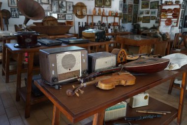 Lardos, Güney Ege bölgesi, Yunanistan - 29 Ağustos 2022: Antik müzik aletleri, fonograflar ve diğer müzik aletleri, radyo cihazları Rodos adasındaki Folklor Müzesi 'ndeki masalarda duruyor. 