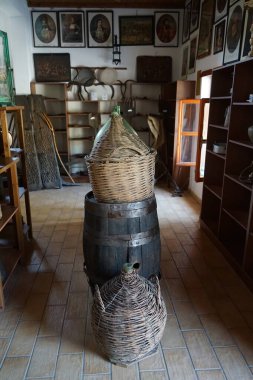 Lardos, Güney Ege bölgesi, Yunanistan - 29 Ağustos 2022: Rodos adasındaki Folklor Müzesi 'nde antika şarap fıçıları ve sepetlerdeki cam şişeler bulunmaktadır..