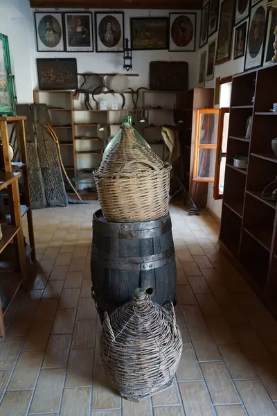 Lardos, Güney Ege bölgesi, Yunanistan - 29 Ağustos 2022: Rodos adasındaki Folklor Müzesi 'nde antika şarap fıçıları ve sepetlerdeki cam şişeler bulunmaktadır..