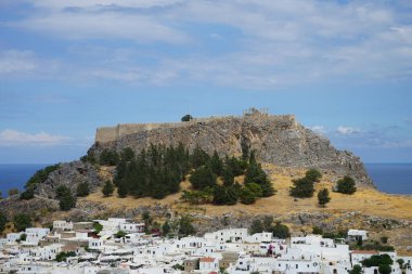 16.-18. yüzyılın beyaz binaları ve ağustosta eski Lindos Akropolü 'nün manzarası. Lindos, Yunanistan 'ın Dodecanese kentindeki Rodos adasında bir arkeolojik alan, bir balıkçı köyü ve eski bir belediyedir..