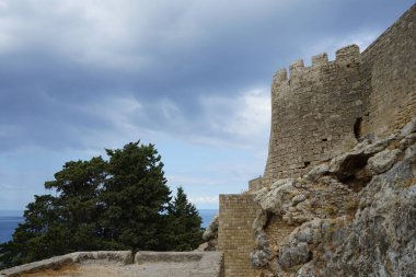 Ağustosta antik Lindos Akropolü 'ndeki kale duvarının manzarası. Bir akropolis, antik bir Yunan şehrinin üst kesimlerinin yerleşim yeriydi. Lindos, Rodos Adası, Dodecanese, Yunanistan  