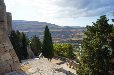 Lindos Akropolü 'ne giden merdivenlerin önündekilere ve patikalara bakın. Bir akropolis, antik bir Yunan şehrinin üst kesimlerinin yerleşim yeriydi. Lindos, Rodos Adası, Dodecanese, Yunanistan