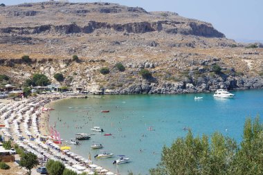 Ağustosta Lindos plajı manzarası. Lindos, Yunanistan 'ın Dodecanese kentindeki Rodos adasında bir arkeolojik alan, bir balıkçı köyü ve eski bir belediyedir..
