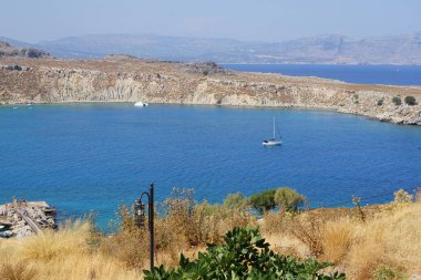 Yelkenliler ve diğer tekneler Lindos açıklarında Akdeniz 'e açılır. Lindos, Yunanistan 'ın Dodecanese kentindeki Rodos adasında bir arkeolojik alan, bir balıkçı köyü ve eski bir belediyedir..